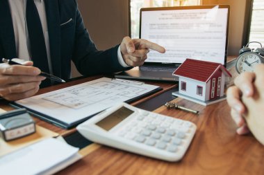 Emlak satış personeli ev ipoteği sözleşmesi belgelerini imza için alıcılara sunar.