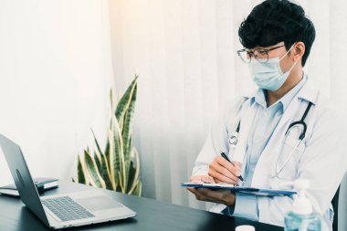 Doktor, elinde kalem tutarak hasta geçmişi listesini panoya yazıyor. İlaç ve tedavi hakkında..
