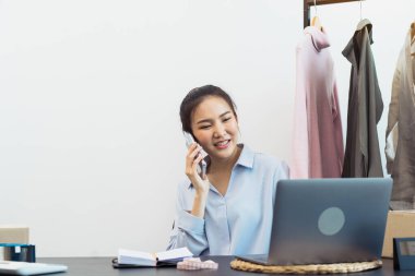 Asyalı girişimci telefonda müşterilerle kamyonetleri hakkında konuşuyor..