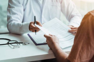 Doktorlar hasta kayıtlarını yapışkan notlarla sunar ve hastalarla ilaçlar ve tedavi hakkında konuşurlar..