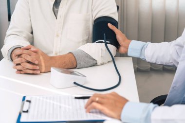 Doktor, üst düzey bir hastanın tansiyonunu ölçüyor..