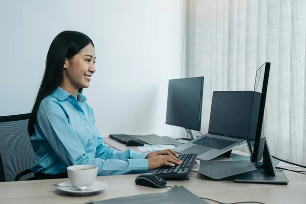 デスクトップコンピュータモニターの専門家に従事し 彼女のオフィスの机に座って 新しいソフトウェアプログラムに取り組んでいるビジネス女性 — ストック写真