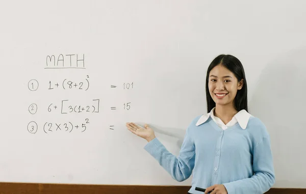Asyalı Bayan Öğretmen Beyaz Tahtadaki Rakamlara Işaret Ederken Sınıftaki Öğrencilere — Stok fotoğraf