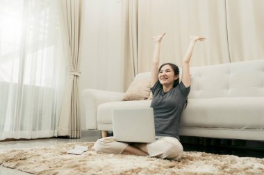 Asyalı kadın dizüstü bilgisayarıyla işini bitirirken kağıtları oturma odasına atıyor..