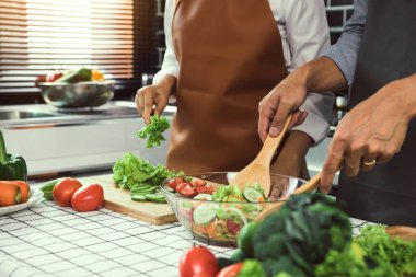 Asyalı çift mutfakta sebze salatası pişiriyor..