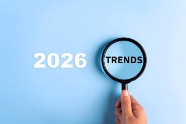 Mavi arka planda büyüteçlere yazılmış TRENDS metni. İş dünyasındaki yeni eğilimler 2026.