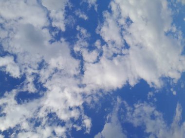 Arkaplanda mavi gökyüzü manzaralı bulutlar var. Mavi gökyüzünde güzel güneşli bulutlar. Güneş kabarık bulutların arasında parlıyor.