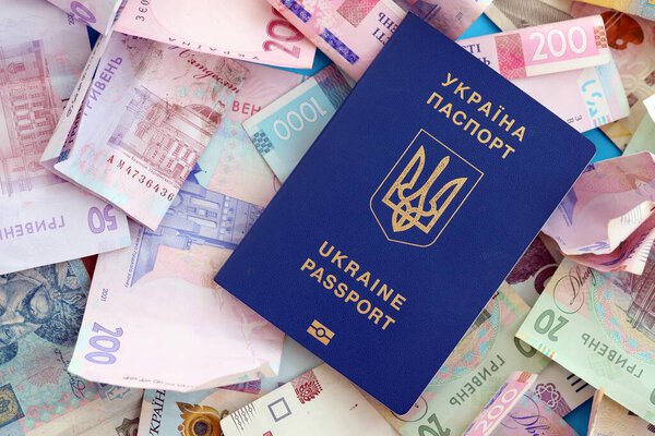 Украинский биометрический паспорт лежит на большом количестве различных украинских гривен денежных счетов крупным планом