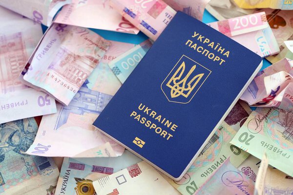 Украинский биометрический паспорт лежит на большом количестве различных украинских гривен денежных счетов крупным планом