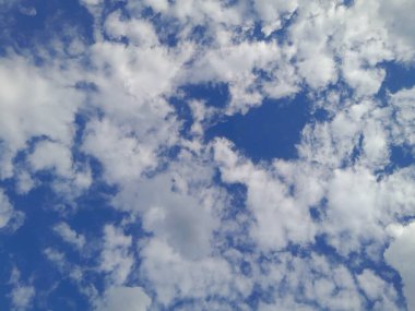 Arkaplanda mavi gökyüzü manzaralı bulutlar var. Mavi gökyüzünde güzel güneşli bulutlar. Güneş kabarık bulutların arasında parlıyor.