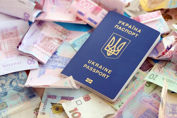 Украинский биометрический паспорт лежит на большом количестве различных украинских гривен денежных счетов крупным планом
