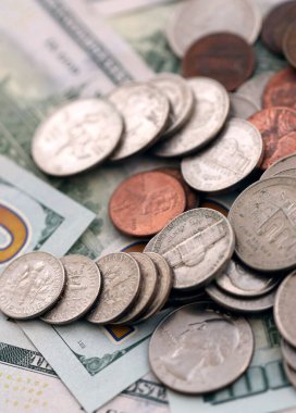 Masada düzensiz bir şekilde düzenlenmiş 100 dolarlık banknotların üzerinde büyük miktarda Amerikan sikkesi var. Para ve iş konsepti