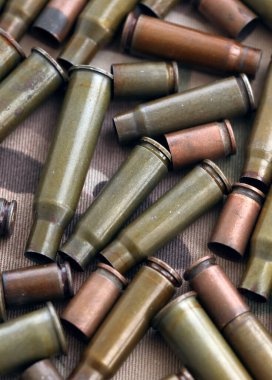 Eski kamuflaj kumaşına isabet eden tüfek mermilerinden çıkan büyük miktarda mermi kovanı. Savaş ve askeri kavram