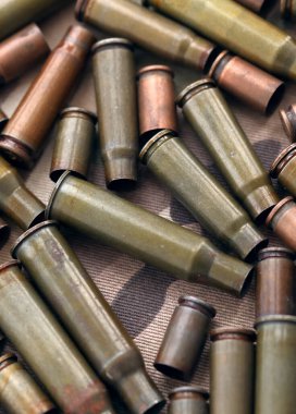 Eski kamuflaj kumaşına isabet eden tüfek mermilerinden çıkan büyük miktarda mermi kovanı. Savaş ve askeri kavram