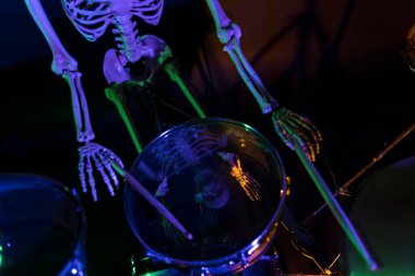 Karanlıkta davul çalarken yansıyan iskelet yüz.