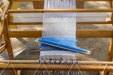 Elle dokuma tezgahında bir kumaş parçasına dokunan mavi yün.