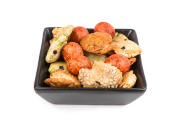 Beyaz üzerine izole edilmiş bir kasede yeşil ve turuncu doğulu atıştırmalıklar.