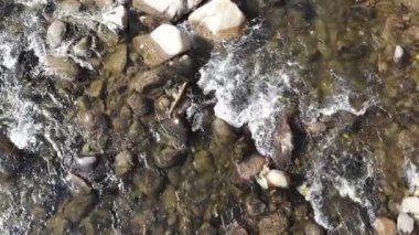 Nehrin yukarısındaki yavaş çekim uçuşunun yukarıdan görünüşü kayaların etrafından akan yeşil nehir suyu.