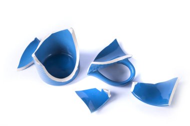 Beyaz arka planda mavi bir kupanın kırık parçaları.