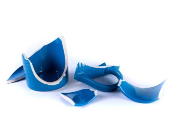 Beyaz arka planda mavi bir kupanın kırık parçaları.