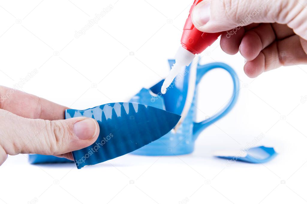 Hand applying glue to a broken piece of cup