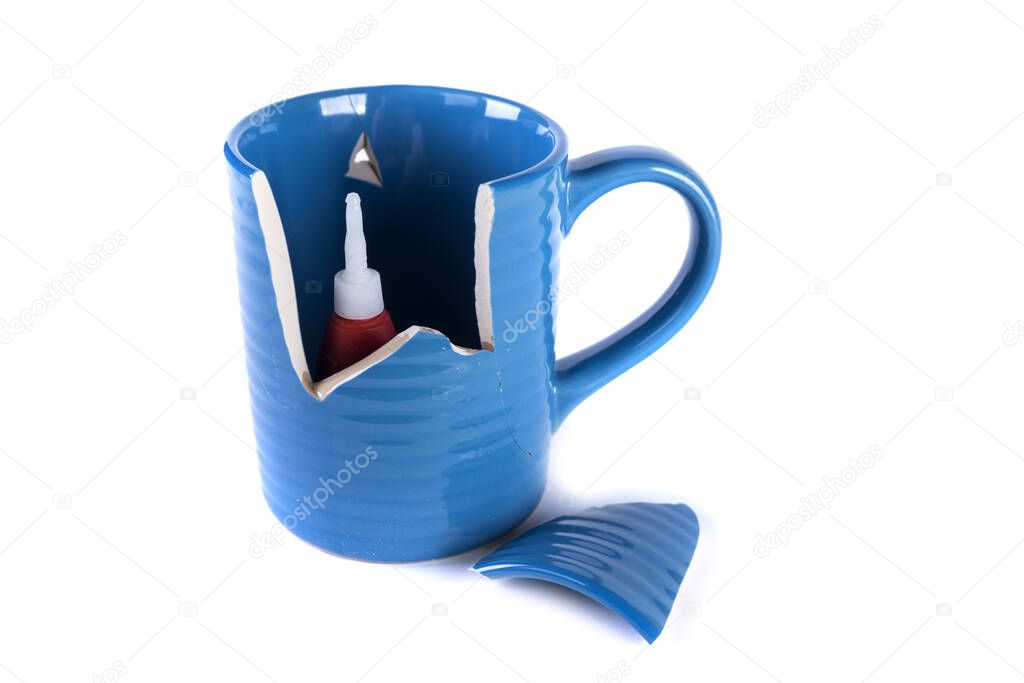 Glue tube sitting inside of a broken blue mug