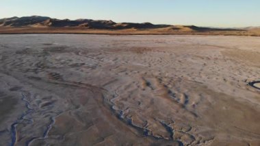 Drone flight over salt wells desert flats weathered by storms and water flow.