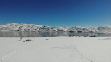  Drone flight liftoff over high sierra lake surrounded by snowy mountains winter reflections in water