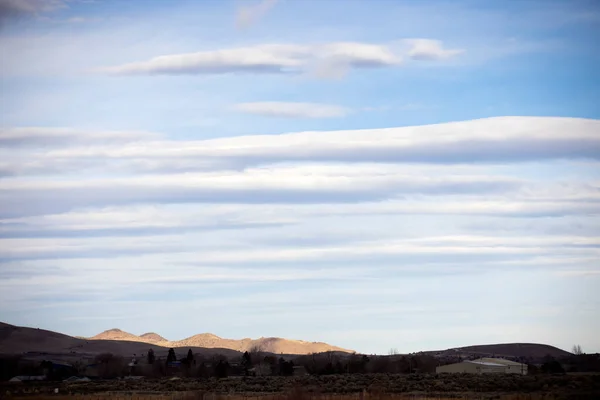 Landscape orientation three quarters of a sky filled with lenticular clouds over desert town carson city