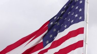 Close up backlit american flag flying from pole on a cloudy day 