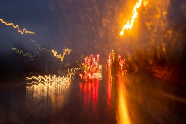 Beyaz kırmızı sarı ve turuncu arka farları olan parlak soyut cadde yağmurlu gecelerde seyahat ediyor.