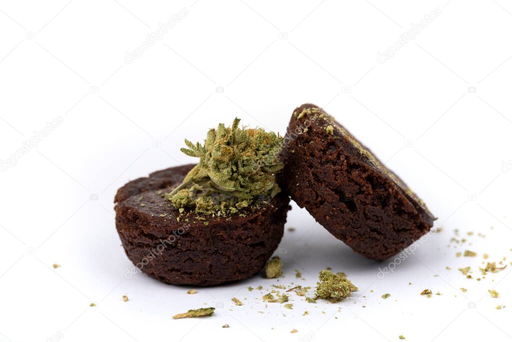 Two special pot brownies with crumbled marijuana isolated over white