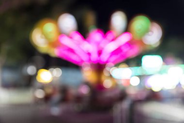 Abstract out of focus carnival ride in motion at night with lights. clipart