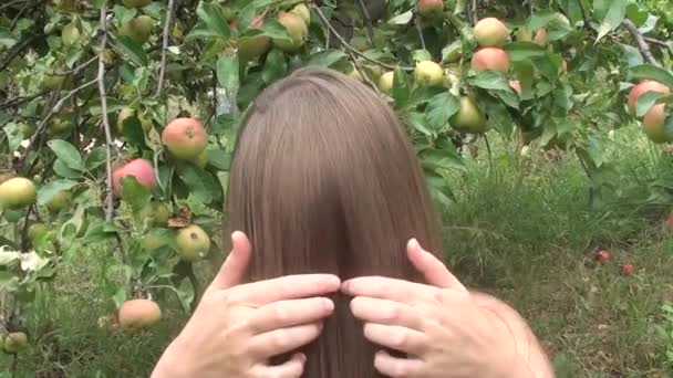 Молода красива дівчина робить смішні обличчя на дачі на фоні яблуні — стокове відео