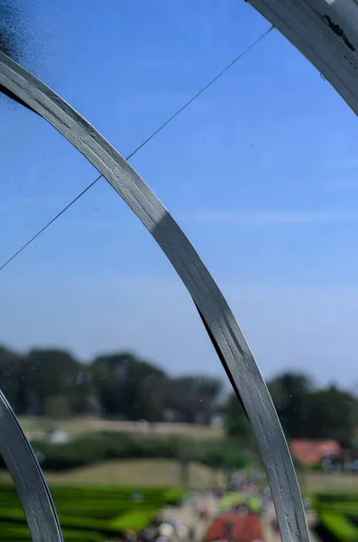 Küresel parlak bir ampulün yakın çekimi, parlak lifini karanlık bir arkaplanda sergiliyor. Şeffaf cam, karmaşık bobin dizaynını ortaya çıkararak sıcak ve çevresel bir ışık yayıyor. Ampul kısmen bir armatürle bağlantılı.