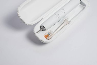 Elektrikli diş fırçası, değiştirilebilir kafa fırçası ve temiz beyaz arka planda seyahat çantası. Günlük diş bakımı, sağlık hizmetleri ve kişisel hijyen konsepti için modern ağız hijyeni cihazı.