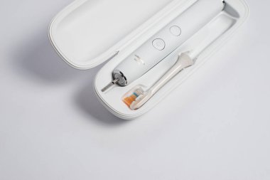 Elektrikli diş fırçası, değiştirilebilir kafa fırçası ve temiz beyaz arka planda seyahat çantası. Günlük diş bakımı, sağlık hizmetleri ve kişisel hijyen konsepti için modern ağız hijyeni cihazı.