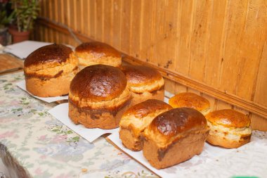 Mutfak masasında altın kahverengi kabuklu taze ev yapımı ekmek somunları. Kırsal stil, sıcak ışık, geleneksel ev yapımı ve konforlu yiyecek konsepti..
