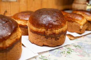 Mutfak masasında altın kahverengi kabuklu taze ev yapımı ekmek somunları. Kırsal stil, sıcak ışık, geleneksel ev yapımı ve konforlu yiyecek konsepti..