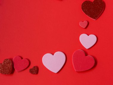Kırmızı yüzeyde dikey bir sınırda dizilmiş pembe, kırmızı ve parıltılı kalplerle sevgililer günü arka planı. Metin için kopyalama alanı olan en az romantik düz alan.