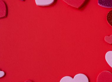 Sevgililer Günü arkaplanı pembe, kırmızı ve parlak kalplerle kırmızı yüzeyde bir çerçeve olarak düzenlenmiş. Metin için kopyalama alanı olan en az romantik düz alan.