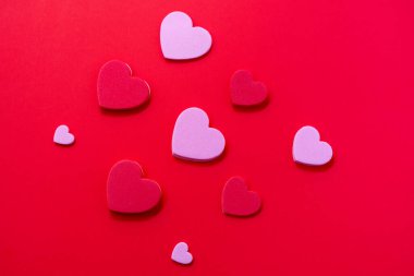 Kırmızı arka planda kırmızı ve pembe kalplerle Sevgililer Günü kompozisyonu. Romantik tatil teması, minimal biçim, kopyalama alanı.