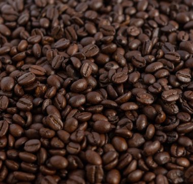 Koyu kavrulmuş kahve çekirdeklerinin detaylı makro görüntüsü zengin kahverengi bir doku yaratıyor. Mutfak arka planı ya da yemek sanayisi duvar kâğıdı olarak kullanılmak için mükemmel..