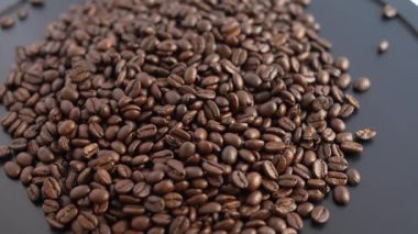 Yukarıdan bir yığın üzerine koyu kavrulmuş kahve çekirdekleri dökülen yüksek kaliteli bir 4K 30 fps videosu. Algılayıcı pazarlama, kafe reklamları ve yemek vlogları için mükemmel olan fasulyelerin orijinal çıtır çıtır sesini içerir..