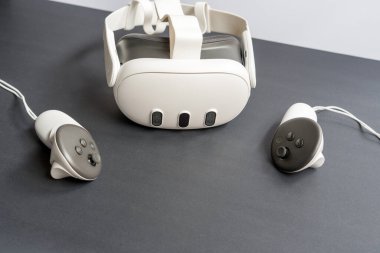 Siyah arka plana yerleştirilmiş iki kontrollü modern sanal gerçeklik kulaklığı. Kapsamlı teknoloji, oyun ve dijital deneyim kavramı.