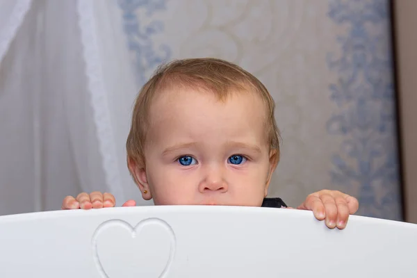 Bambina sbircia fuori dalla culla bianca — Foto Stock