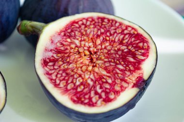 Yakın çekimde olgun incirlerin fotoğrafı var. Kırmızı posa ve olgun mor incir taneleri..