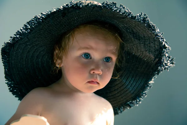 Klein schattig meisje in een zwart strand hoed met brede rand — Stockfoto