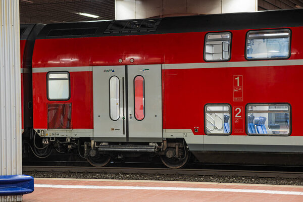 Kassel, Germany - 01.11.2025: A red double-decker passenger train at a deserted station at night. The car is illuminated from the inside, and empty seats are visible on a regional train in Germany.