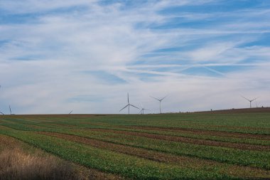 Gökyüzü mavi gökyüzü, uçaklardan gelen bir sürü zıtlık, bir yarık alanı ve ufukta gökyüzü ile tarla arasında birçok rüzgar türbini var..